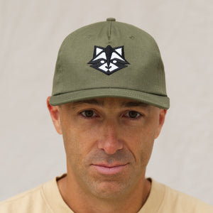 Front View of the Raccoon Baseball Hat in Army Green Cotton Canvas on top of a man wearing the hat. Embroidered raccoon head design on the crown.  